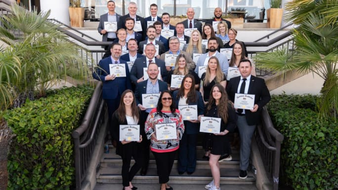 A graduating class holding up certificates.