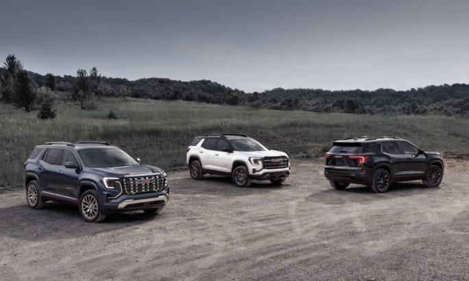 A lineup of GMC Terrains in Elevation, AT4, and Denali trims parked on a dirt road.