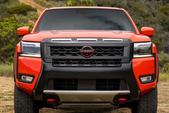 The front grille of an orange Nissan Frontier.