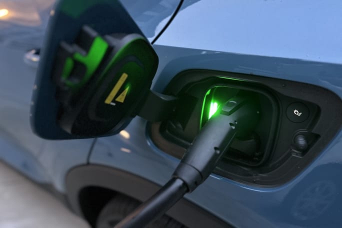 Close up shot of an electric charger plugged into a blue electric car.