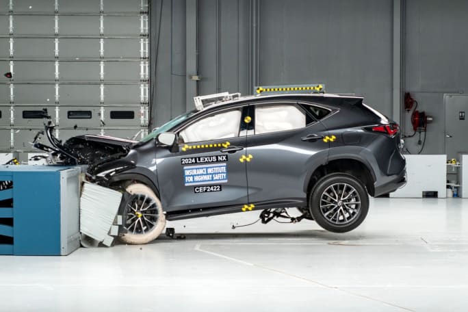 A gray Lexus NX in a crash testing room mid-crash.
