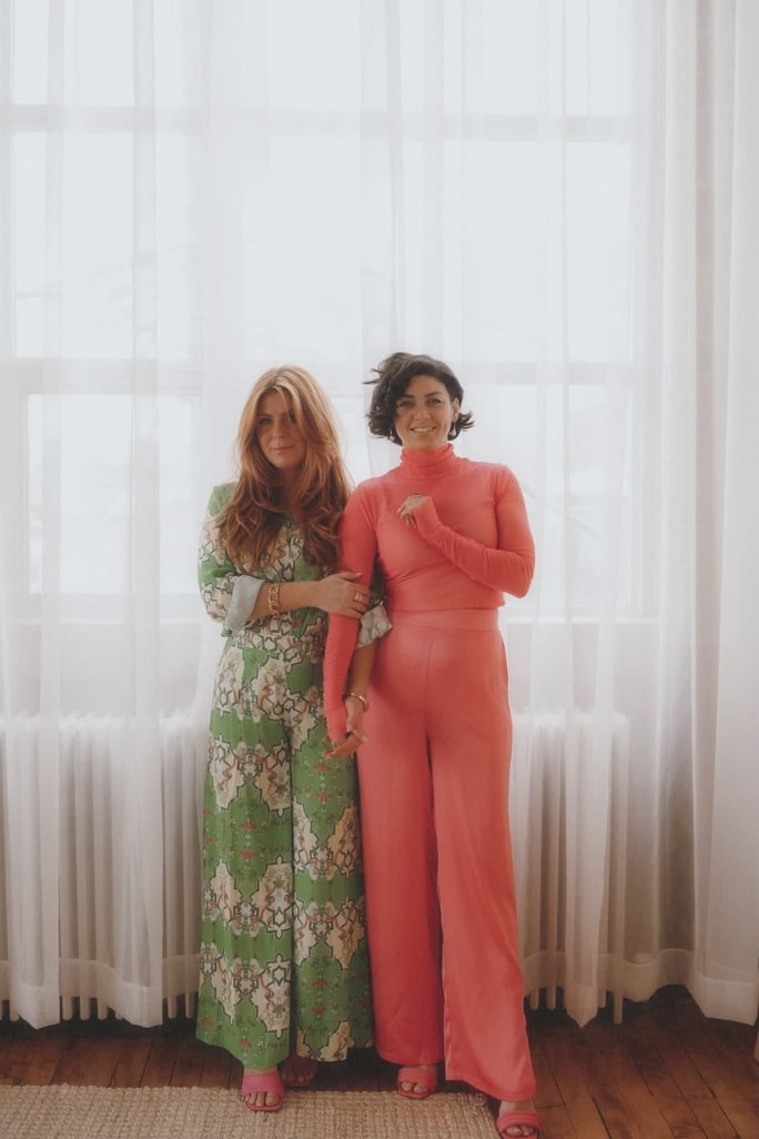 Shampoo Society owners Bailey Neto and Sophie Brindamour stand in front of sheer drapes in their salon.