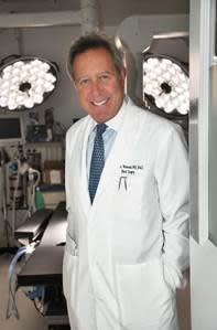 A smiling man in a white doctor's coat.