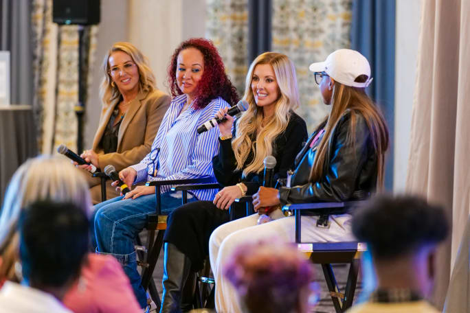 Four women on a panel with one holding a microphone