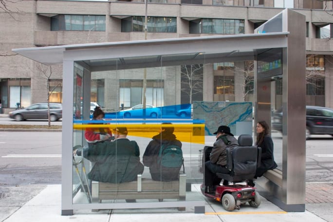 Riders wait at a covered bus stop for a Société de transport de Montréal bus.