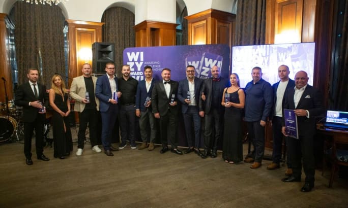 Award winners lined up in a ballroom holding their award memorabilia.
