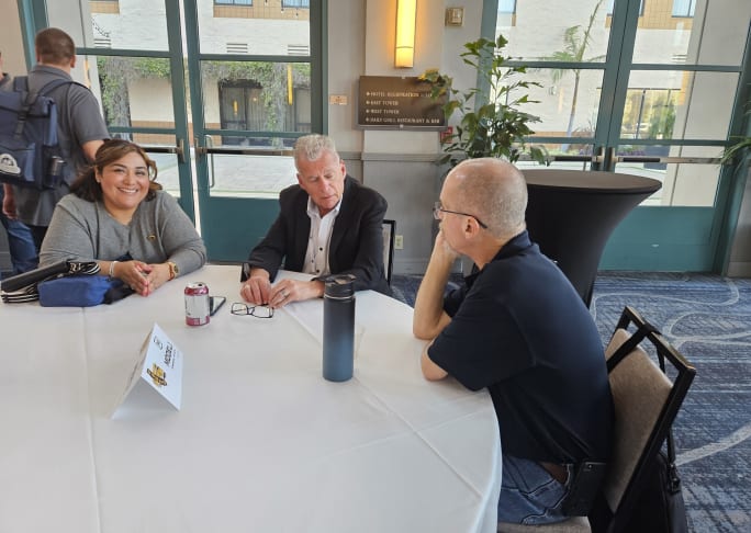 three people have a discussion at a table