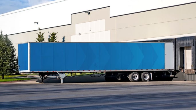 Blue trailer backed up to dock at shipper facility