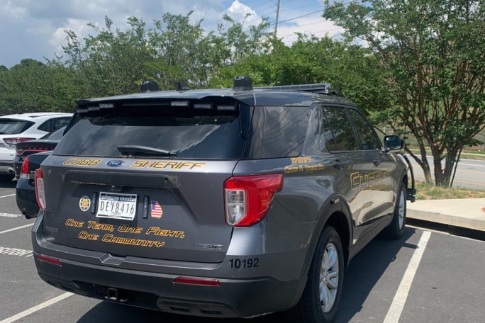 A gray Ford PIU Hybrid with a gold Cobb County Sheriff's Office decal sits in a parking lot.