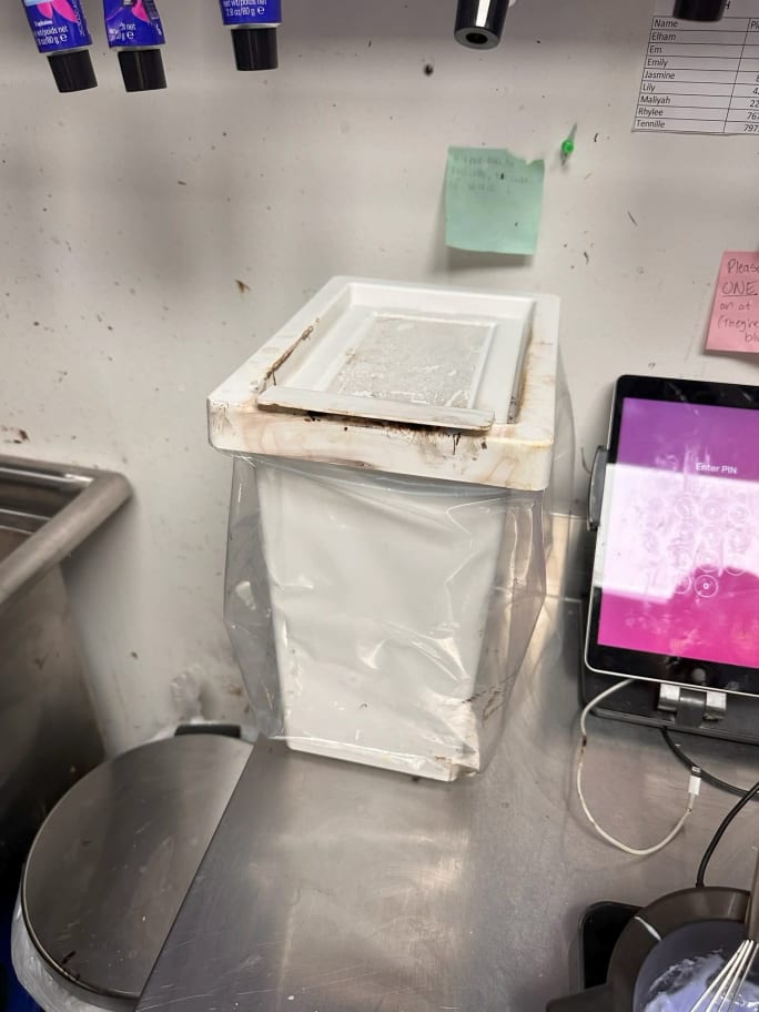A small plastic trash bin in a color room
