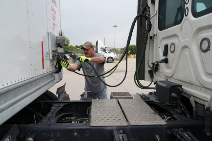 Truck driver checking the connections between tractor and trailer
