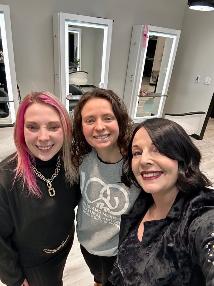A mother and her two daughters smiling in the salon