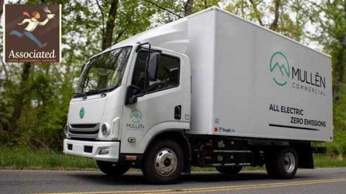 A Mullen all-electric box truck driving on a road.