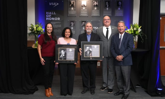 A group of people holding up two VIA Hall of Honor plaques.