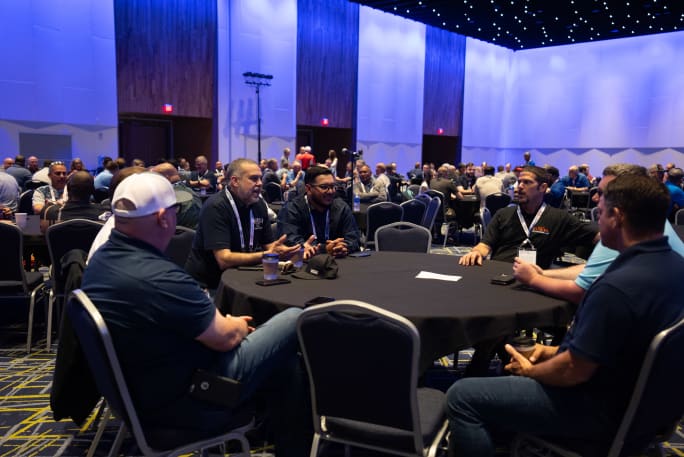 A group of fleet professionals sits at a table discussing common fleet problems and solutions to those problems.