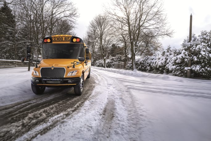 an IC electric school bus drives on a snowy road