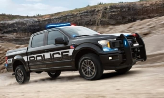 Black police pickup truck with blue emergency lights in rocky terrain