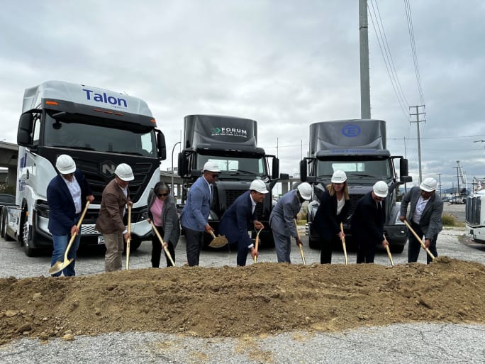 Executives in hardhats shovel dirt in a ceremony.