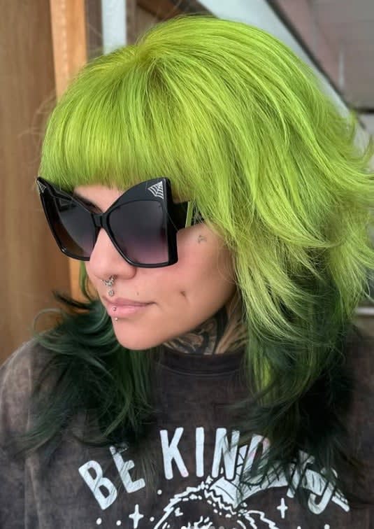 Model with light green hair and big dark sunglasses.