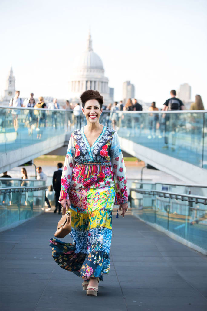 A woman walking in front of a large building.