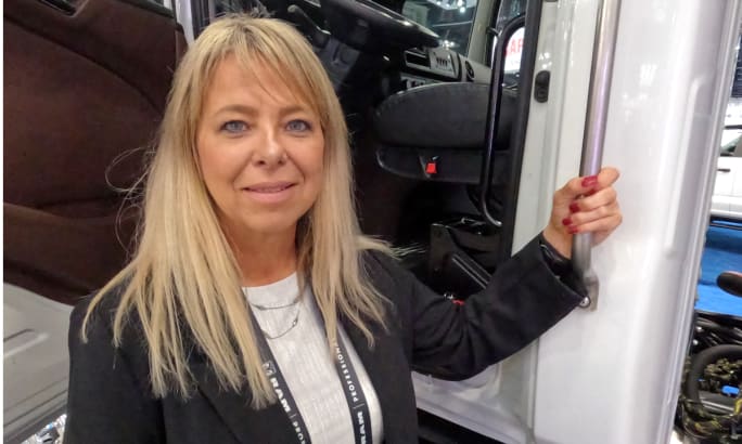 Woman holding grab handle of a large white truck.