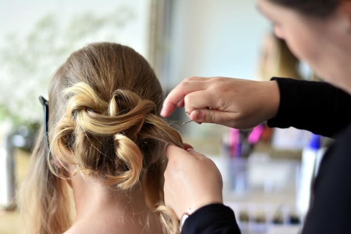 A hairstylist creating an upstyle on a client