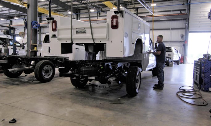 A technician works on a Knapheide service body in a repair shop.