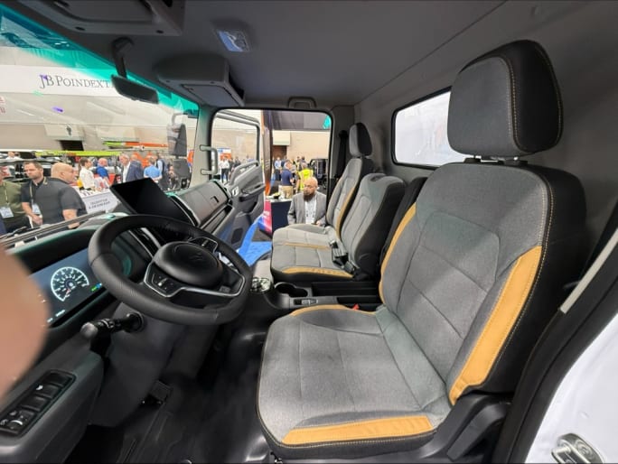 Interior of Harbinger HC Series Cab work truck showing steering wheel, digital gauges, center display, and three-seat cab layout on the Work Truck Week show floor.