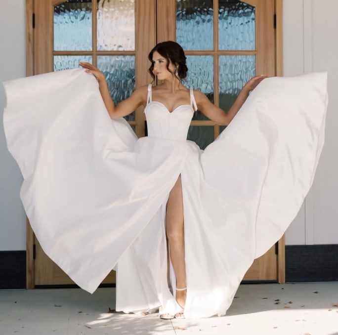 A bride spreads the layers of her skirt like bird wings
