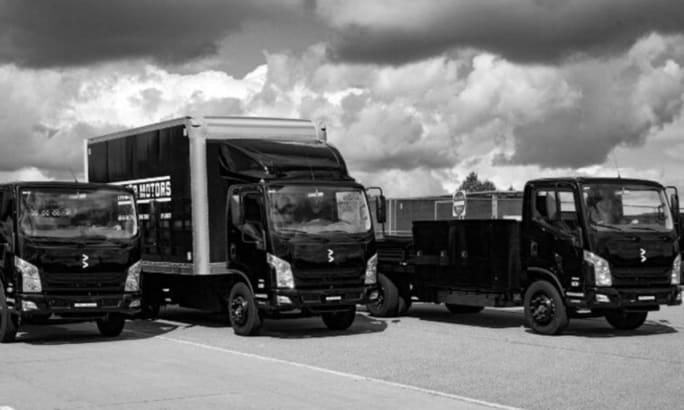 A black and white photo of a Bollinger Motors B4 EV Truck lineup.