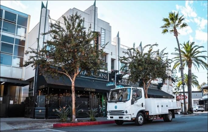 A Mullen Automotive truck outside businesses.
