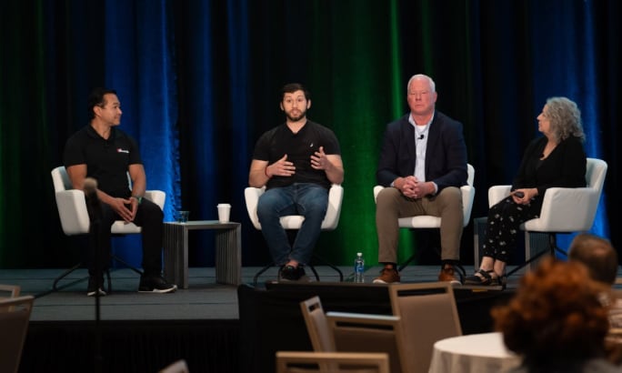 A group of panelists sitting and talking on a stage.