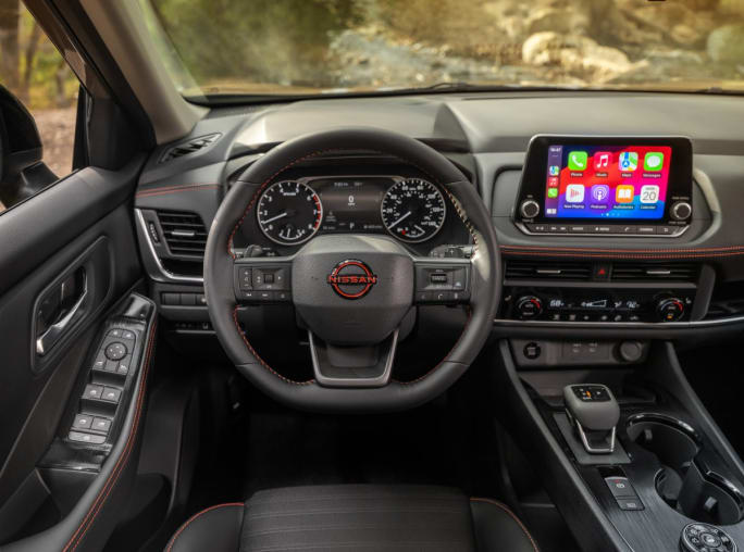 The interior, steering wheel, and dashboard of a Nissan car.