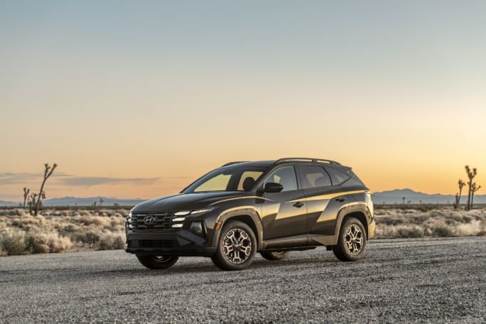 A Black 2025 Tucson parked on a road with a desert and cactus in the background.