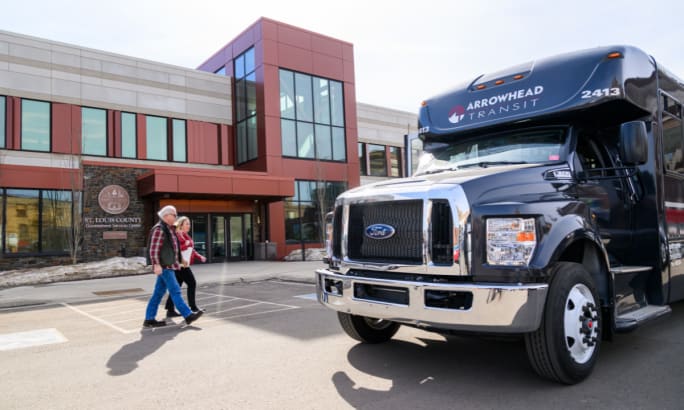 Riders walk up to an Arrowhead Transit bus.