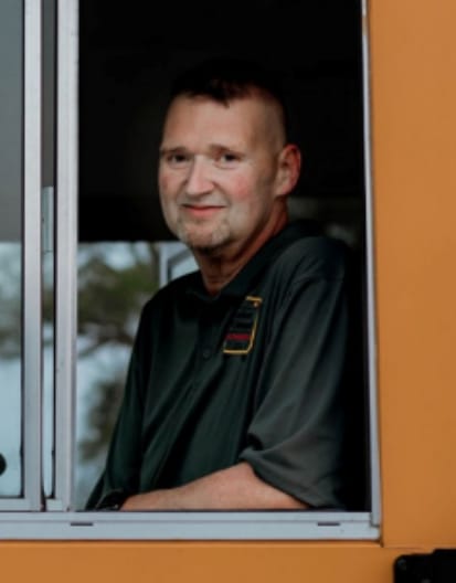 Portrait of Nelson Smith through the driver window of a school bus.