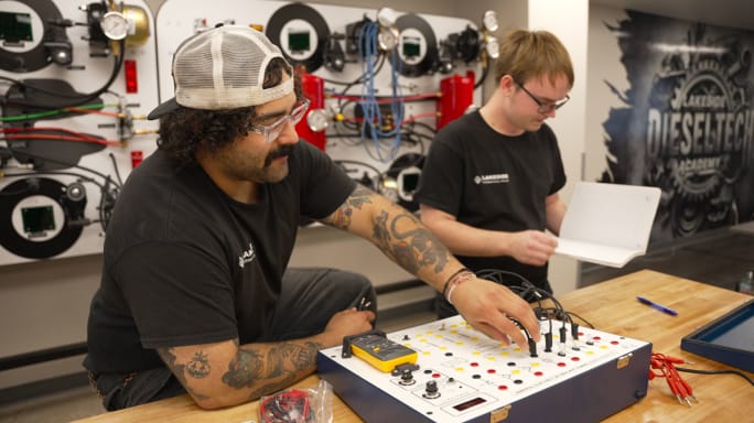 Two male diesel technician students using Ohm's Law Trainer