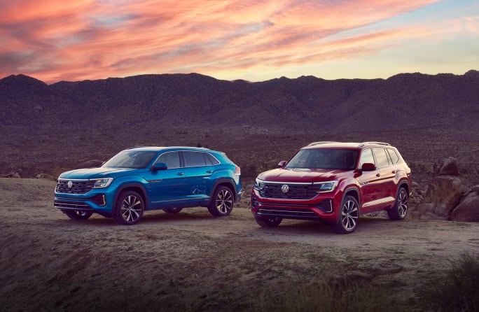 A blue Atlas sits next to a red Atlas Cross Sport in front of mountains.