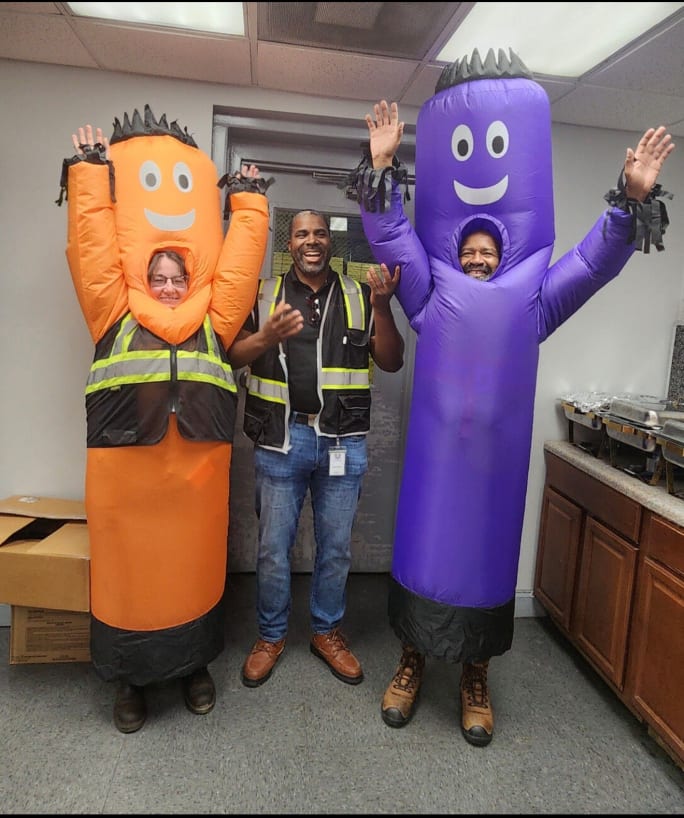 Jerrin Martin laughing with employees dressed in orange and purple costumes