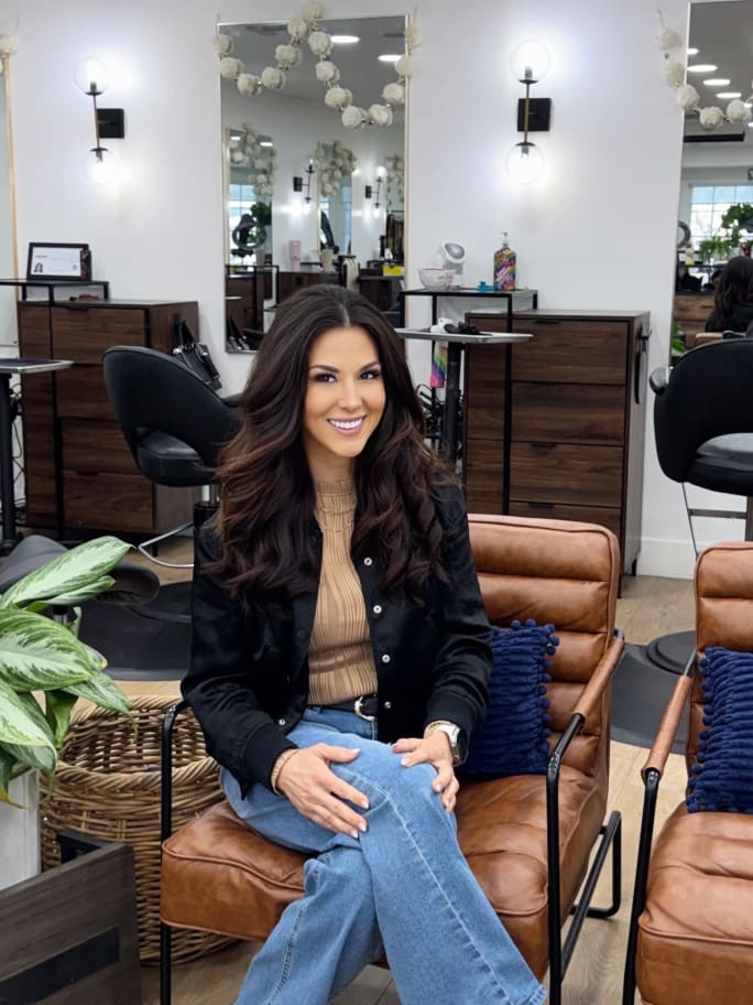 Lucy Randall seated in a modern salon space, representing strategic content planning and coordinated campaigns that strengthen client retention.