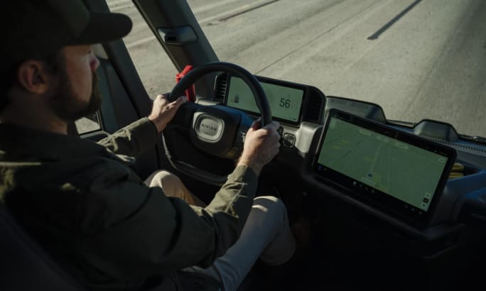 Front cab interior of the Rivian commercial van's driver seat, dashboard, and infotainment center.