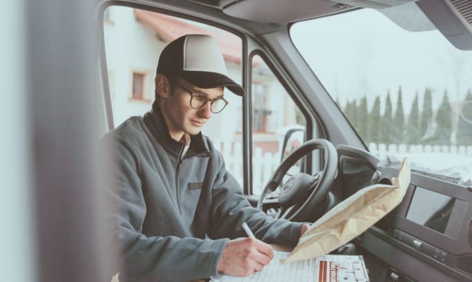 Image of a delivery person filling out forms inside a vehicle.