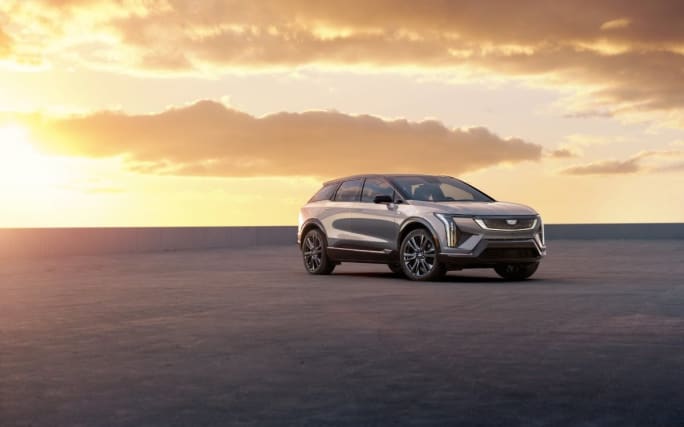 A silver SUV parked in front of an orange sunset.
