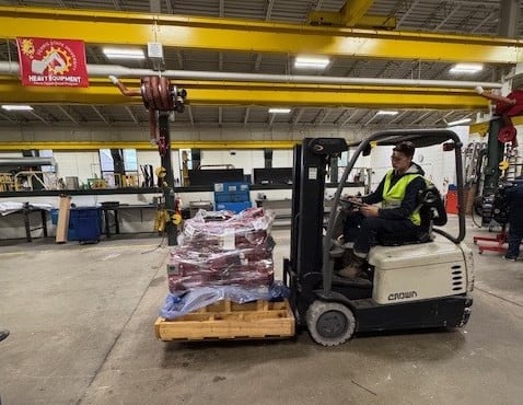 Image of a forklift operator moving a diesel engine.