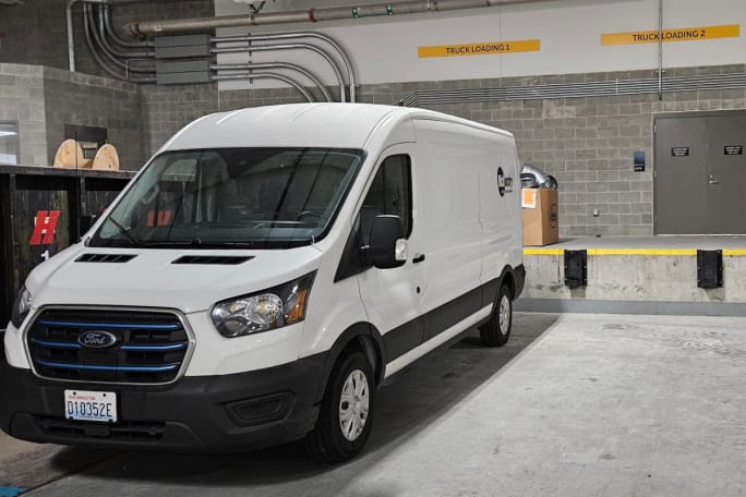 A McKinstry Express van — a white Ford E-Transit — is seen at a loading dock. The vans are used to make deliveries to job sites.