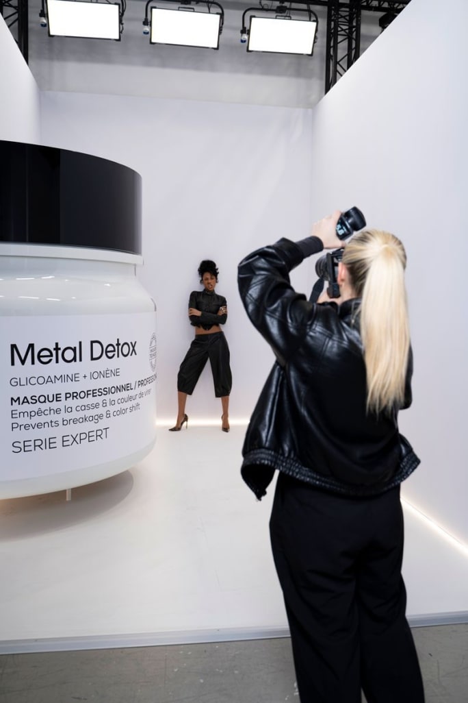 A photographer holds her camera up as a model strikes a pose at Transformation Day