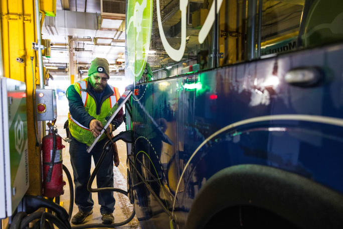 Maintenance tech charging an electric bus.