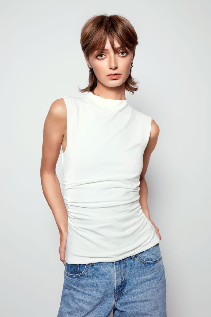 A woman in white tshirt and jeans and light brown hair.