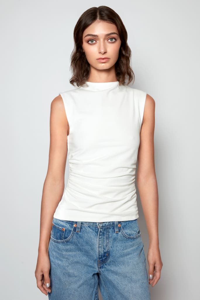 A woman in white t shirt and jeans, and medium brown hair.