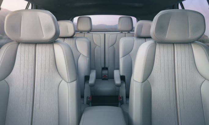 View from the front seat of a 2026 Cadillac Vistiq showing all three rows of seats with a light colored fabric.